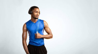 Fitness Modeli. Kulaklık takan kendine güvenen Afro adam sarı stüdyo duvarının üzerinde boynuna ip bağlayıp,