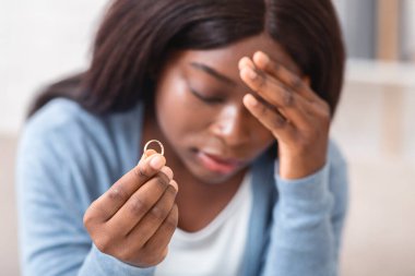 Divorce concept. Desperate heartbroken african american woman holding wedding ring, feeling depressed about ruined marriage and breaking up, closeup clipart