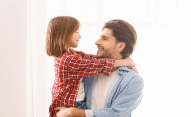 Küçük tatlı kızın portresi gülümseyen babasına bakıyor, babasının kızını beyaz arka planda tutması, kopyalama alanı.