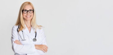 Steteskoplu kadın doktor gri arka planda poz veriyor. Kopya alanı olan panorama.