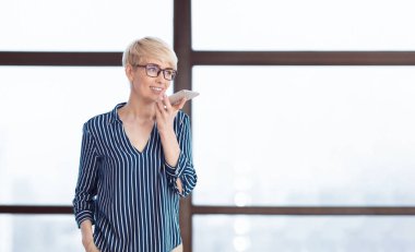 İş İletişimi. Modern Ofisteki Pencerenin Yakınındaki Hoparlörden Konuşan Olgun Kadın. Panorama, Boşluk