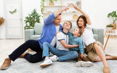 Aile için konut. Genç ebeveynler el ele tutuşuyor sembolik ev çatısı yapıyorlar. Çocuklarla birlikte yeni dairede oturuyorlar..