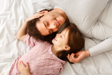 Sevgi dolu bekar baba ve tatlı kızının birbirlerine bakıp gülümsemelerinin, evde uzanmalarının, yeni uyanmalarının, şefkatli bir konsept olmasının en güzel görüntüsü.