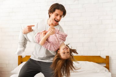 Genç ve yakışıklı bir baba, anaokulu kızıyla evde oynuyor.
