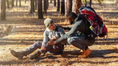 Zenci adam yaralı arkadaşına yardım ediyor, ormanda yürüyüş yapıyor, mekanı kopyalıyor.