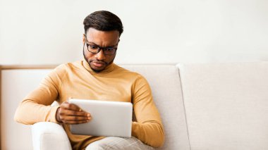 Ciddi Afro Girişimci Evdeki Koltukta Oturan Dijital Tablet Kullanıyor. Seçici Odaklanma