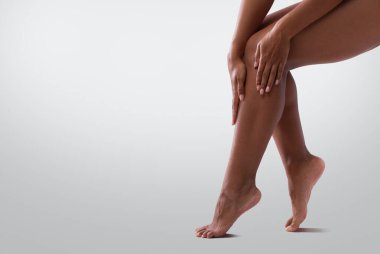 Cropped of female legs, black woman touching her skin after waxing or epilation, copy space clipart