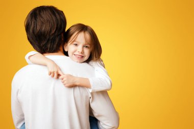 Küçük tatlı kız sarı stüdyo geçmişi yüzünden babasına sarılıyor.