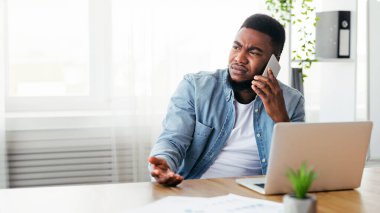 Başarısızlık ve kriz konsepti. Üzgün Afro-Amerikan çalışanı ofisinde otururken telefonla kötü haber alıyor, boşluğu kopyalıyor.