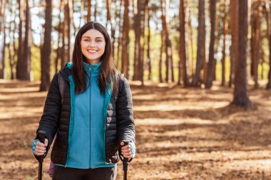 Mutlu kız kameraya gülümserken çok ırklı erkekler güzergahı tartışıyor, ormanda yürüyüş yapıyor.