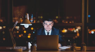 İşadamı geceleri dizüstü bilgisayarda çalışıyor modern ofiste panoramik manzaralı oturuyor. İş kariyeri. Boşluğu Kopyala, Panorama