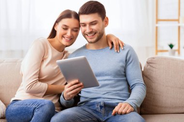 Hafta sonu. Neşeli Eşler Dijital Tablet kullanarak Evdeki Koltukta Oturan Film İzliyor. Seçici Odaklanma