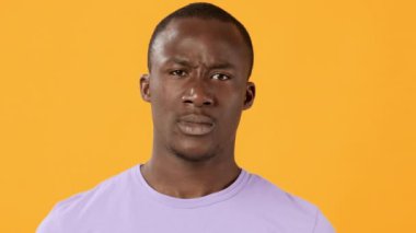 Genç bir adam güçlü duygular gösterir. Güçlü yumruklar ve sert bir ifadeyle canlı turuncu bir zemin üzerine kurulur. Bir anlık enerji ve tutku yakalar..