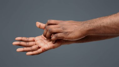 Deri iltihabı. Elini kaşıyan afro bir adam. Kırpılmış, beyaz bir arka plan.