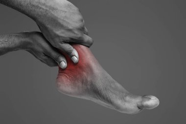 Cropped of african man rubbing his ankle over white background, copy space