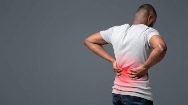 Afro guy holding both hands on lower back, pain in spine, inflamed zone highlighted in red, white background, free space