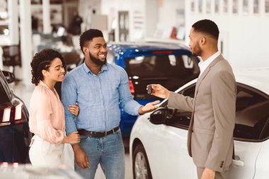 Araba kiralama konsepti. Otomobil Kiralama Ofisinde Bekleyen Yöneticiden Otomobil Anahtarı Alan Afro Çift.