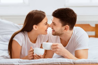 Birlikte hafta sonu. Sevgi dolu çift sabah kahvesini evde yatakta içiyor..