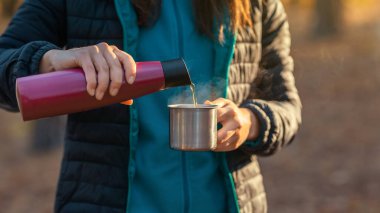 Kamp bardağına çay döken kadın ellerini kapat.