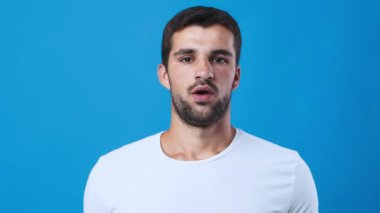 Bir adam içeride nefes alma tekniği uyguluyor. Burnuna bir cihaz dayayıp nefesine odaklanıyor. Arka plan koyu mavi, beyaz gömleğini tamamlıyor..