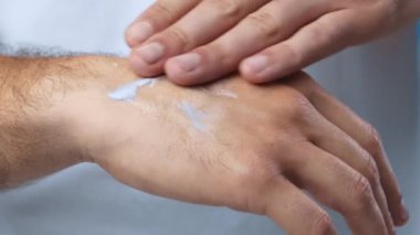 Bir insan kuru ellerine nemlendirici krem sürüp, hidrasyon ve cilt bakımına odaklanır. İçerideki ortam aktivitenin görünürlüğünü arttırmak için iyi ışıklandırmaya sahiptir..