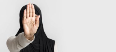 Tanımlanamayan tesettürlü müslüman kadın, el hareketini durduruyor ya da reddediyor. Avuç içi açık, açık arka plan, panorama