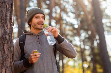 Sırt çantalı genç yürüyüşçü içme suyu, ormanda mola, boş alan