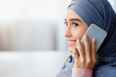 Modern İletişim. Müslüman bir kadının cep telefonuyla konuşmasının ve başka yere bakmasının yakın plan portresi.