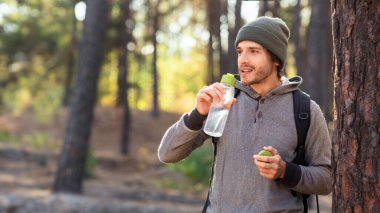 Çam ormanlarında yürürken su içen yakışıklı adam, boşluğu kopyala