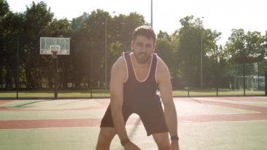 Genç bir adam akşam ışığında dışarıda sahada antrenman yaparken top sürüyor..