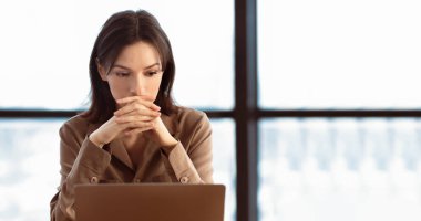 Uzaktan kumanda. Düşünceli bayan yönetici, kafenin içindeki panorama 'da dizüstü bilgisayarla blog yazma fikri üzerine kafa yoruyor.