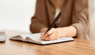 Kişisel Planlayıcı. Çalışma yerinde otururken deftere yazan, not alan, plan çizelgesi hazırlayan, kopya alan