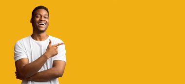 Reklam Kavramı. Sarı stüdyo arka planında izole edilmiş fotokopi alanını gösteren mutlu siyah adam.