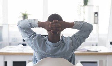 İşte mola. Afro-Amerikan işçilerin işyerinde dinlenirken, elleri başının arkasında sandalyeye yaslanırken,