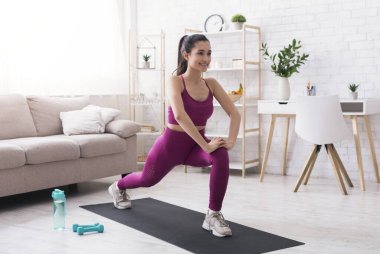 Evde kal, aktif kal. İspanyol kız oturma odasında kardiyo çalışması yapıyor.