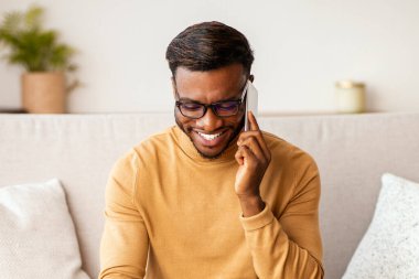Her zaman temastayız. Laptop kullanan Afro Adam 'ın evdeki koltukta oturup keyifli bir telefon konuşması yapması ne güzel. Seçici Odaklanma