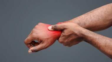 Romatizmadan muzdarip, bileğine masaj yapan afro bir adamın görüntüsü.