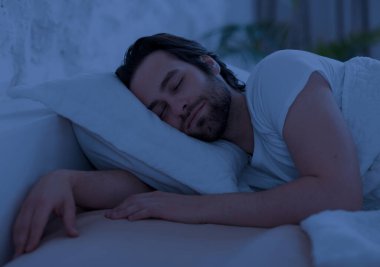 Barışçıl yakışıklı sakallı genç adam evde tek başına rahat bir yatakta uyuyor, ortopedik yatağının, yastığının, yan bakışının, fotokopi alanının tadını çıkarıyor. İyi uykular.