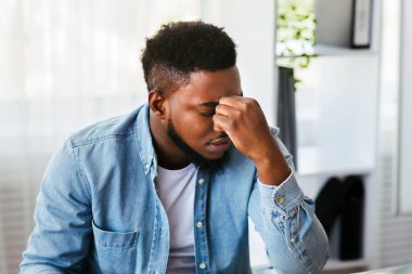 Yorgun Afrika kökenli Amerikalı çalışanlar burun köprüsüne masaj yapıyorlar, ofiste uzun süre çalışmaktan yoruldular, uzay kopyaları yapıyorlar.