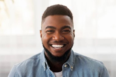 Yüzünde mutlu bir gülümseme olan yakışıklı Afrikalı Amerikalı adamın yakın plan portresi.