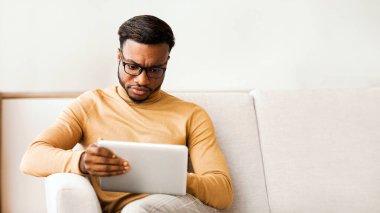 Ciddi Afro Girişimci Evdeki Koltukta Oturan Dijital Tablet Kullanıyor. Seçici Odaklanma