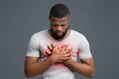 Sad young afro man suffering from acute pain in chest, white background