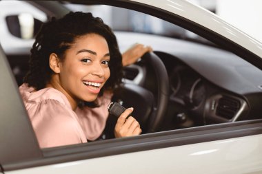 Yeni Araba Konsepti. Neşeli Siyah Kadın Alıcı Otomobil galerisinde Sürücü koltuğunda Otomatik Anahtarı Gösteriyor. Seçici Odaklanma