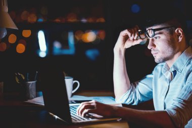 İşçilik. Çok çalışan iş adamı laptopta çalışıyor. Gece geç saatlere kadar modern ofiste oturuyor..