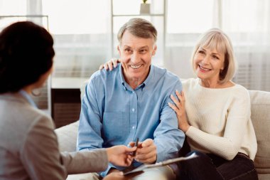 Sigorta Konsepti. Mutlu son sınıf çifti evde bayan ajana danışıyor, kağıtları imzalıyor.