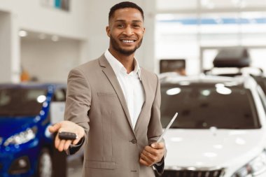 Otomobil satıcısı, oto galerisinde duran Smiliing 'e otomobil anahtarı teklif ediyor. Seçici Odaklanma