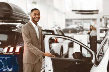 Araba fuarı. Gülümseyen Kara Satıcı Otomobil Açılış Kapısı Otomobil Satış Merkezi 'nde duruyor. Seçici Odaklanma