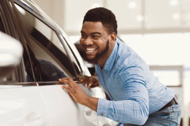 Mutlu Araba Sahibi. Yeni aracına dokunan Afrikalı adam galeride otomobil alacağı için heyecanlı. Seçici Odaklanma