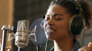 Afrikalı Amerikalı bir kadın, müzik stüdyosunda duygusal bir performans sergiliyor..