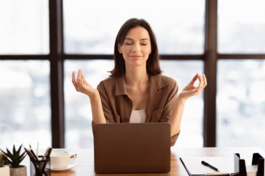 Zihinsel hijyen. Sakin, güzel bir kız iş yerinde meditasyon yapıyor, stres ve endişeyle boğuşuyor. Boş boşluk